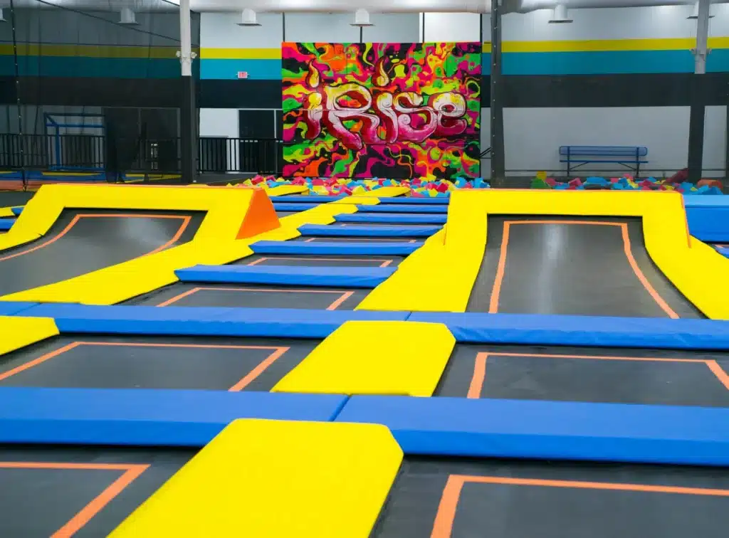 A large indoor trampoline park with obstacles and ramps.