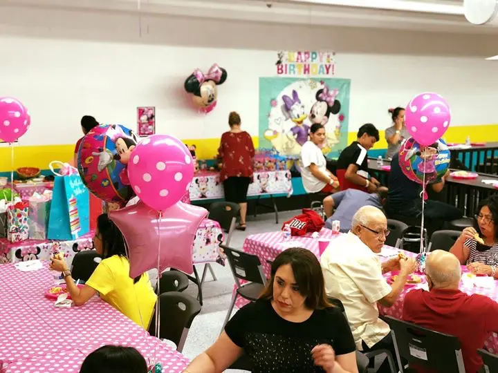 A group of people sitting at tables with balloons.