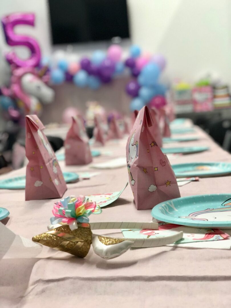 A table with pink and blue plates, napkins and paper bags.
