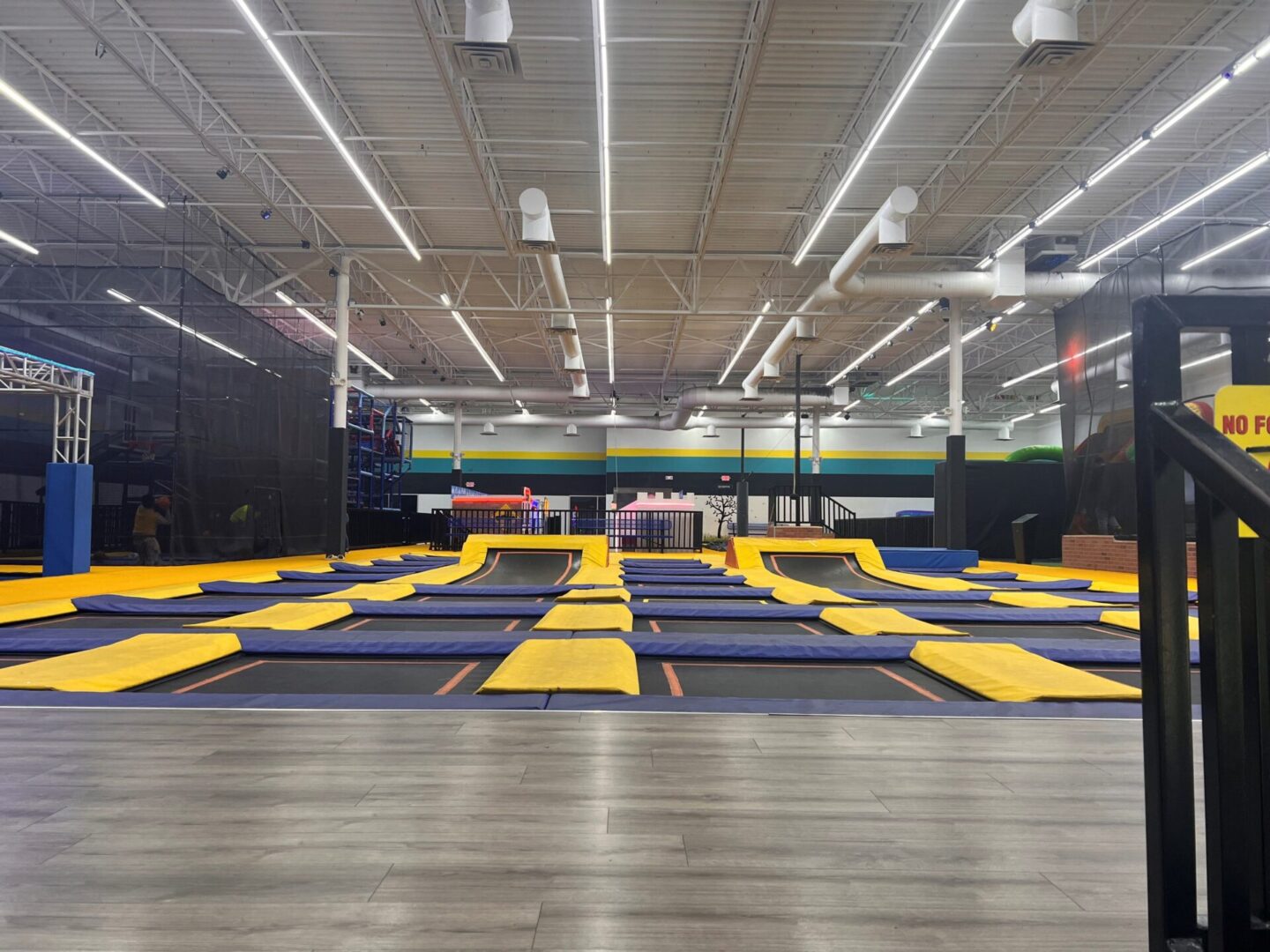 A large indoor trampoline park with many different trampolines.