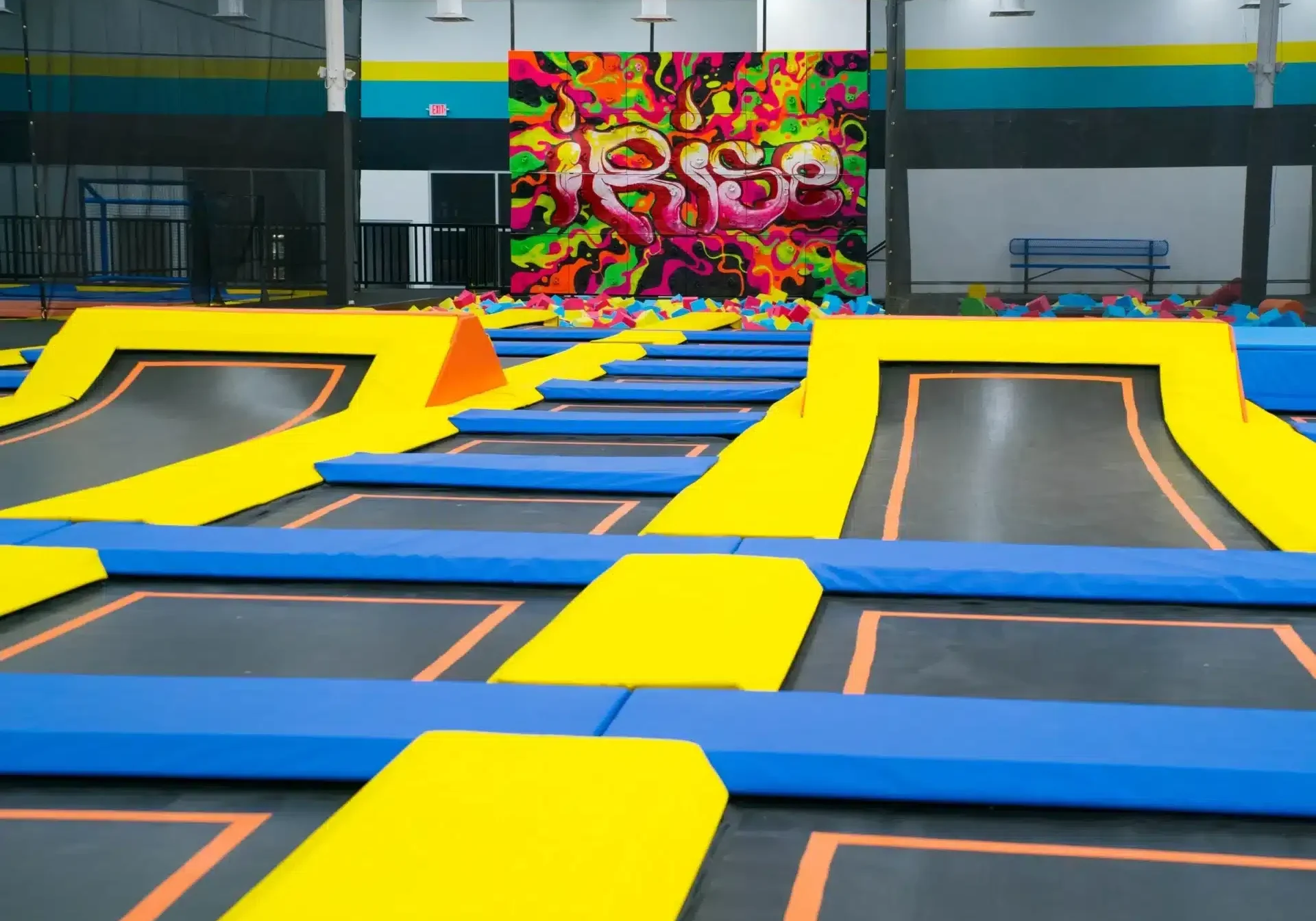 A large indoor trampoline park with obstacles and ramps.
